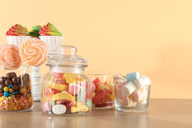 Photo of Candy bar. Many different sweets on wooden table against beige background. Space for text