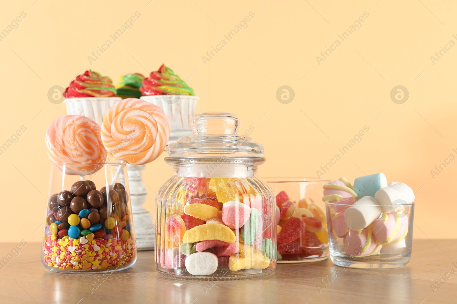 Photo of Candy bar. Many different sweets on wooden table against beige background. Space for text