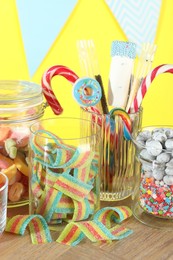 Photo of Candy bar. Many different sweets on wooden table against yellow background, closeup