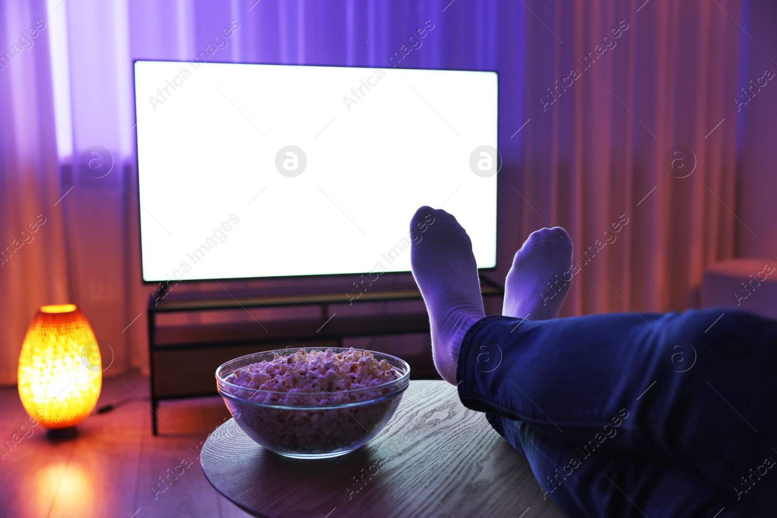 Photo of Woman with popcorn watching tv in evening at home, closeup