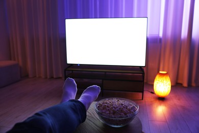 Photo of Woman with popcorn watching tv in evening at home, closeup