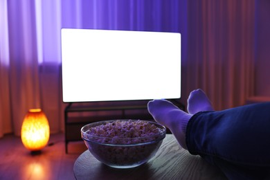 Photo of Woman with popcorn watching tv in evening at home, closeup