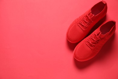 Photo of Sportive shoes. Pair of stylish sneakers on crimson background, flat lay. Space for text