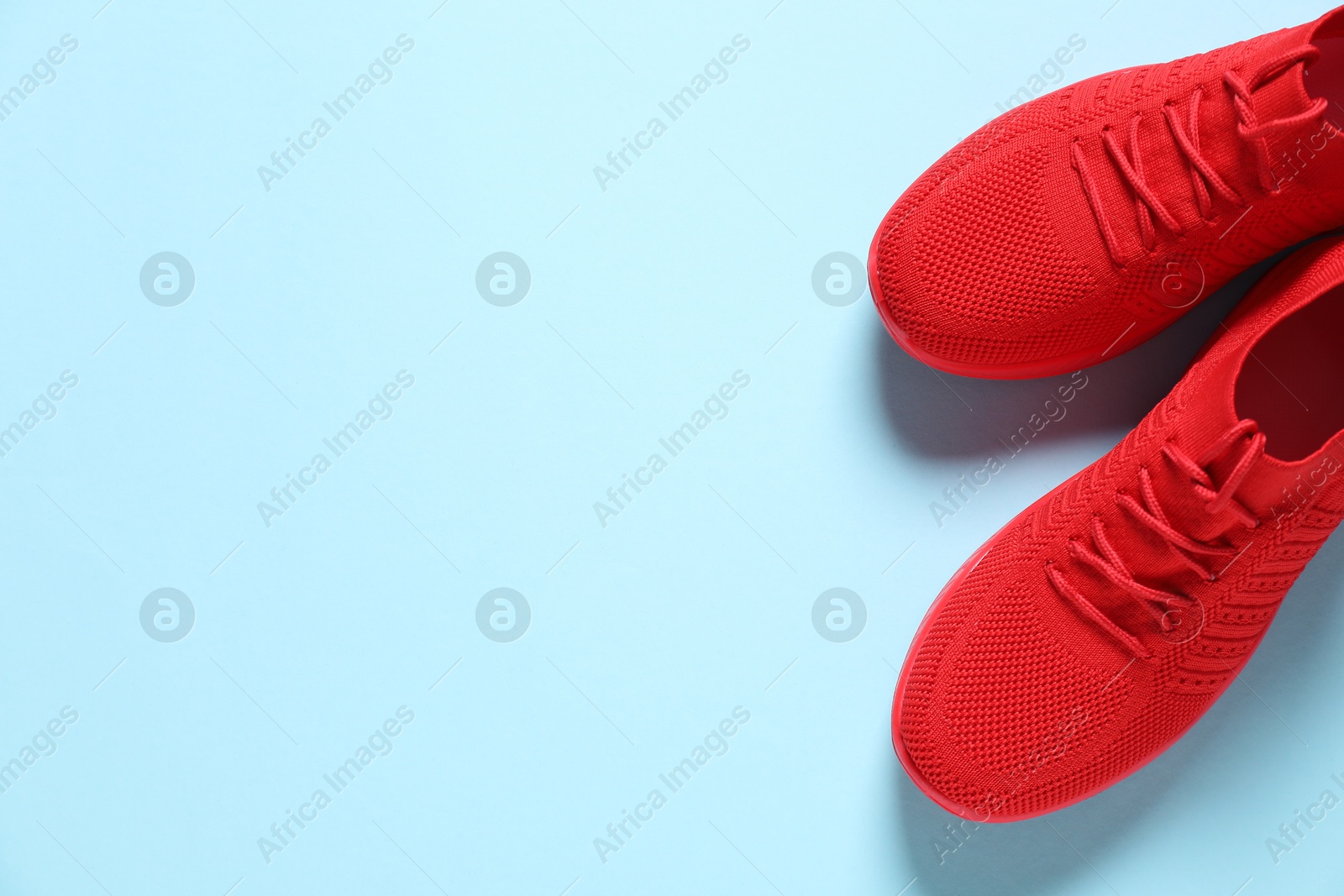 Photo of Sportive shoes. Pair of stylish sneakers on light blue background, flat lay. Space for text