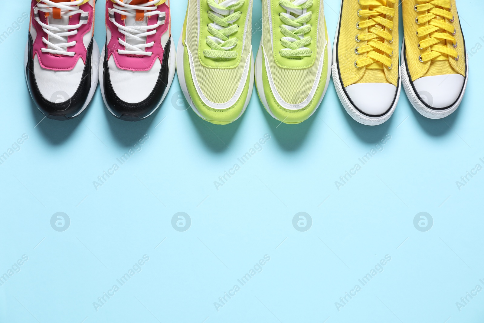 Photo of Sportive shoes. Different sneakers on light blue background, flat lay. Space for text