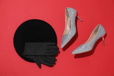 Photo of Shiny high heeled shoes, beret and gloves on crimson background, flat lay