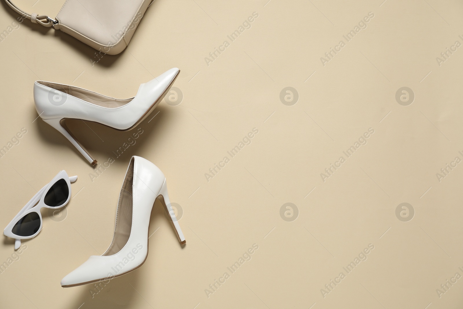 Photo of White high heeled shoes, bag and sunglasses on beige background, flat lay. Space for text