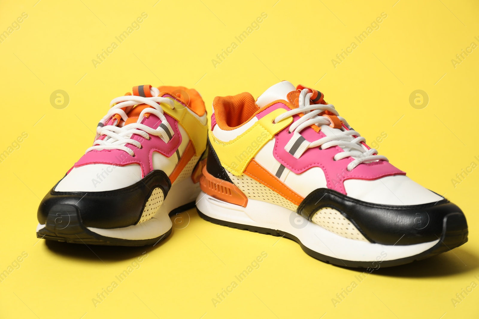 Photo of Stylish sneakers on yellow background. Sportive shoes