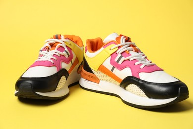 Photo of Stylish sneakers on yellow background. Sportive shoes