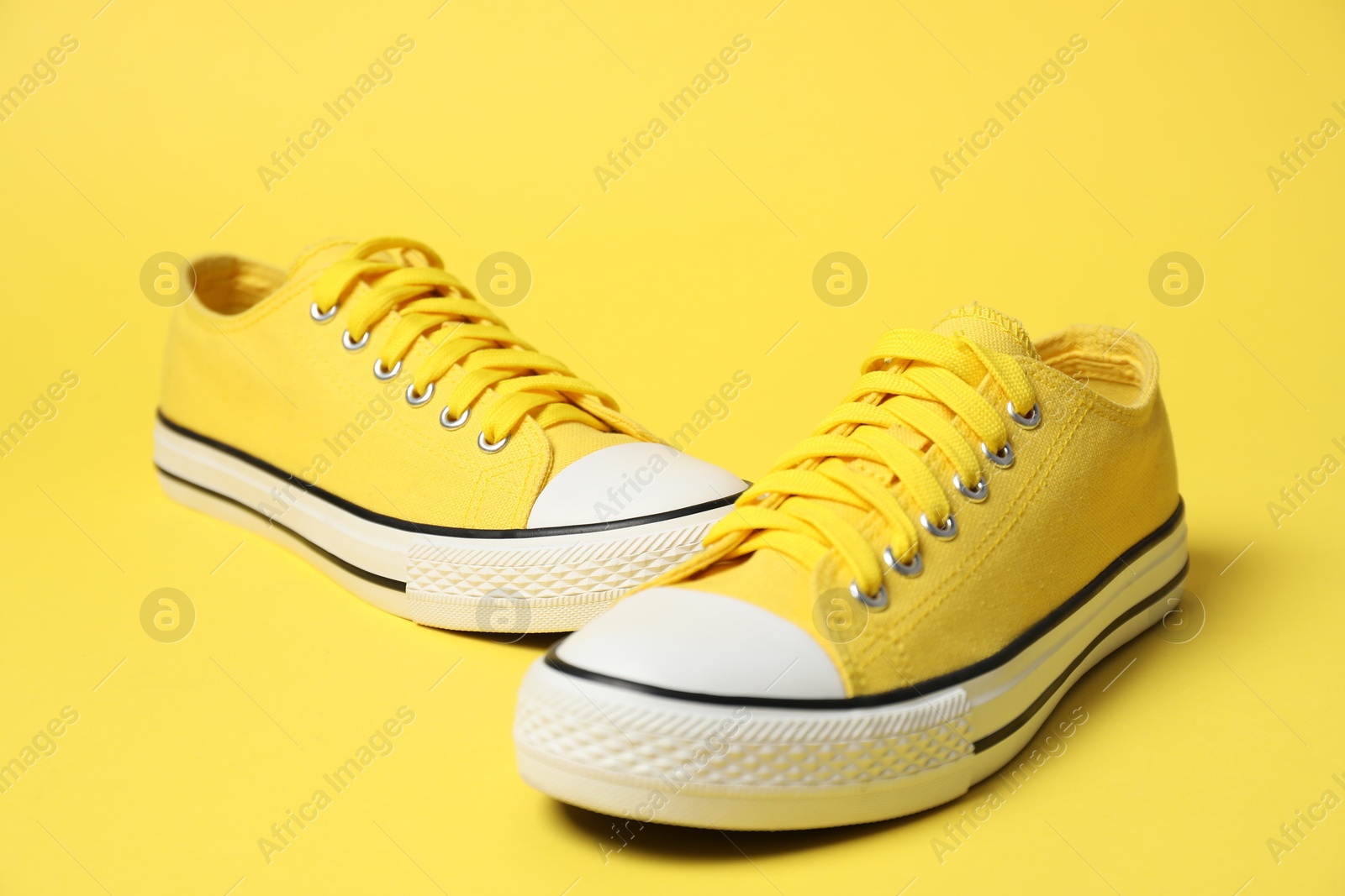 Photo of Color sneakers on yellow background. Sportive shoes