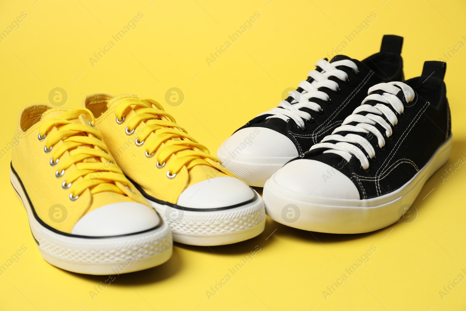 Photo of Stylish sneakers on yellow background. Sportive shoes