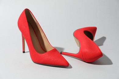 Photo of Red high heeled shoes on light background