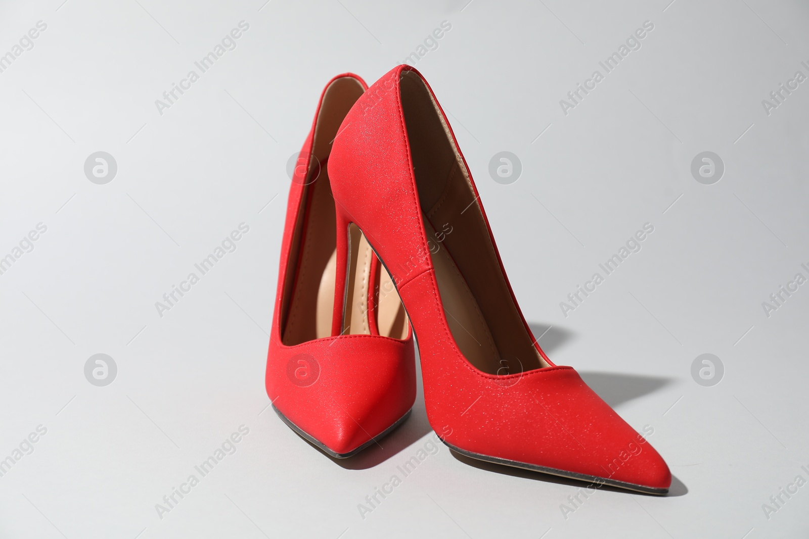 Photo of Red high heeled shoes on light background