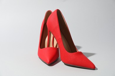 Photo of Red high heeled shoes on light background