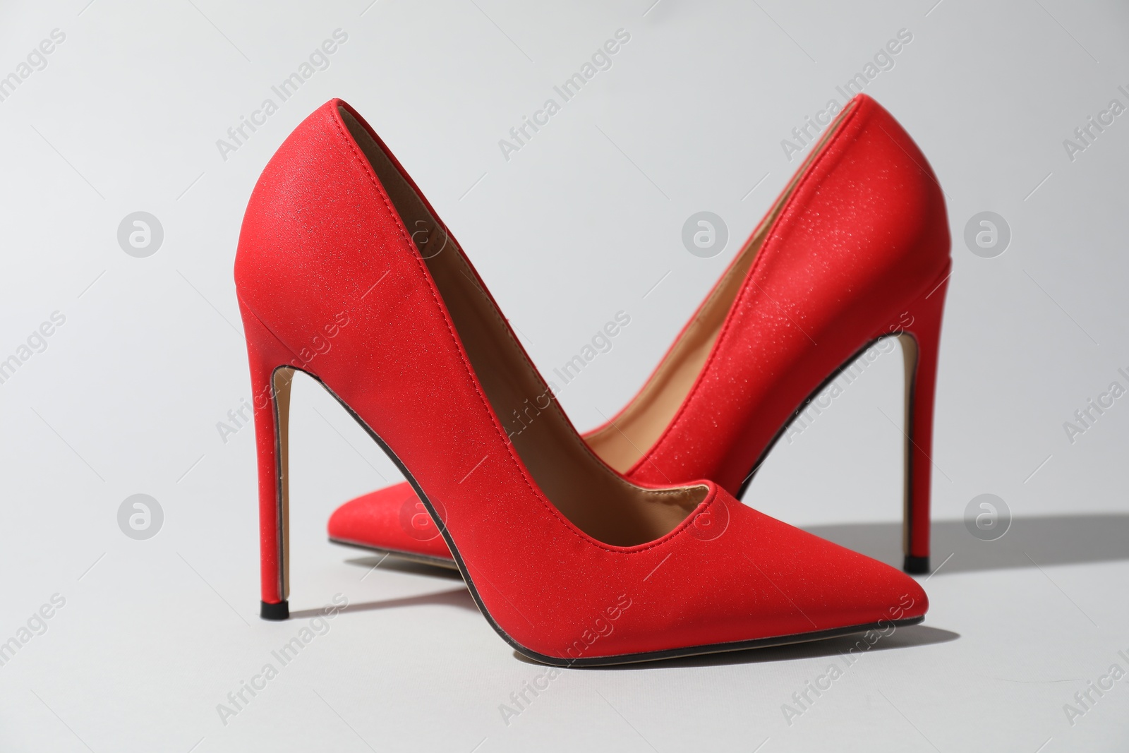 Photo of Red high heeled shoes on light background