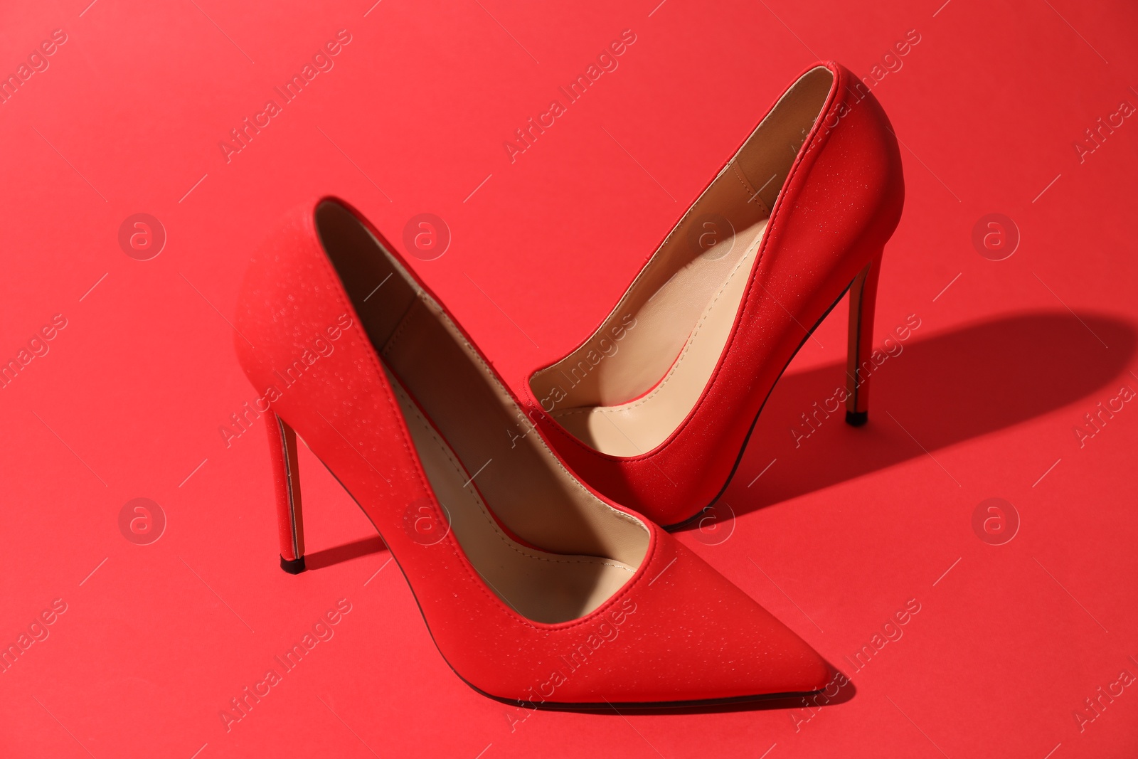 Photo of Beautiful high heeled shoes on crimson background