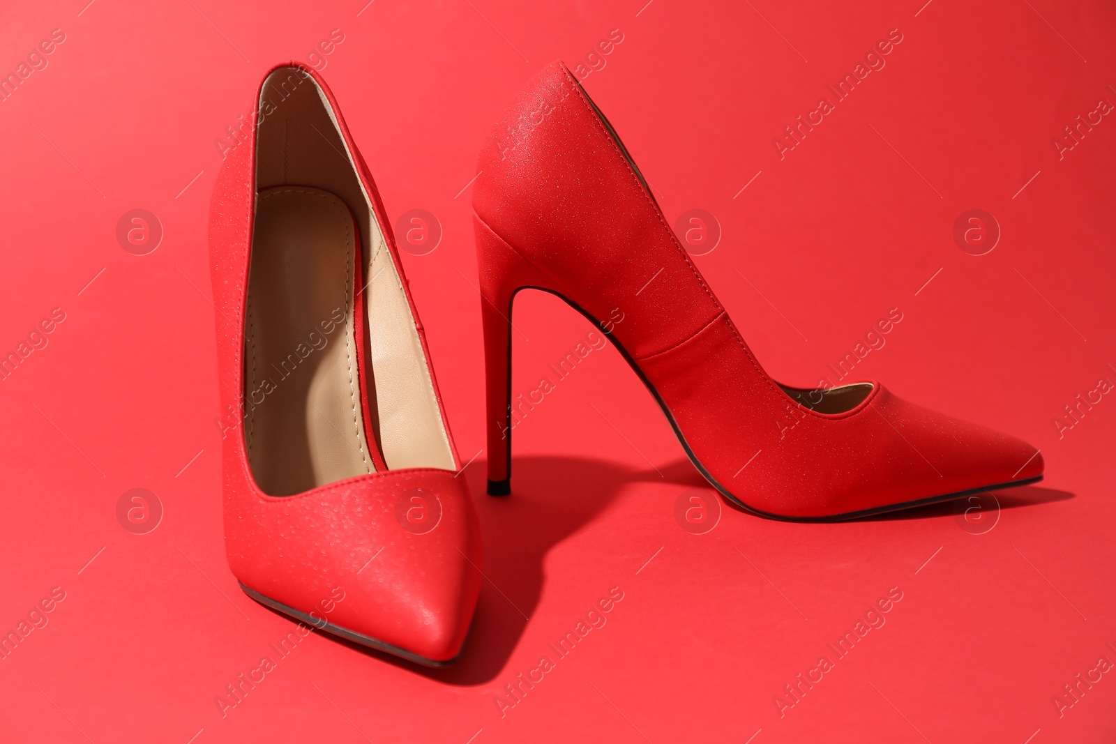 Photo of Beautiful high heeled shoes on crimson background