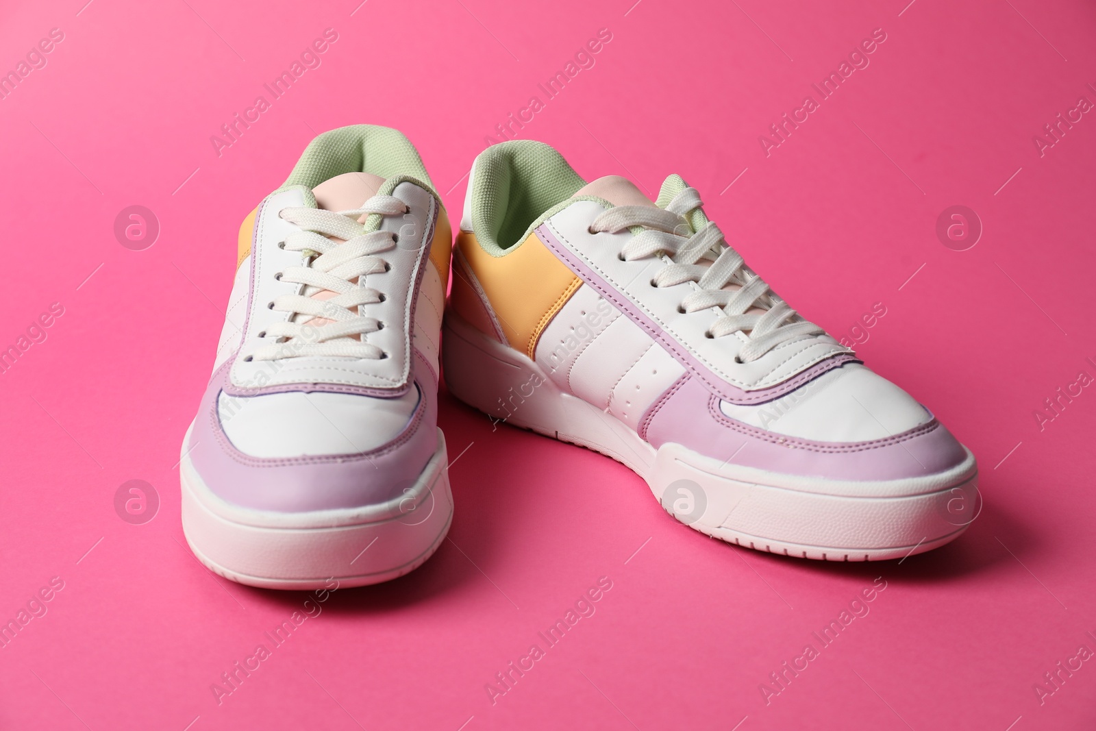 Photo of Stylish sneakers on pink background. Sportive shoes