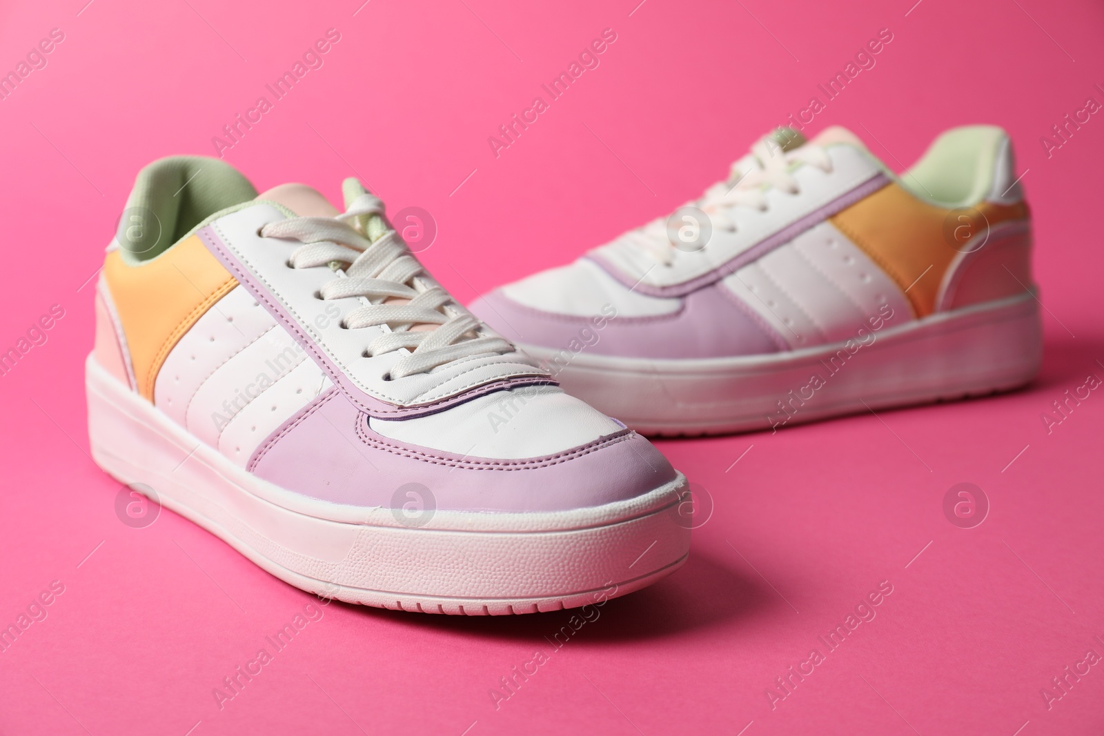 Photo of Stylish sneakers on pink background, closeup. Sportive shoes