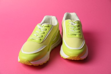 Photo of Green sneakers on pink background. Sportive shoes