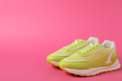 Photo of Sportive shoes. Green sneakers on pink background, space for text