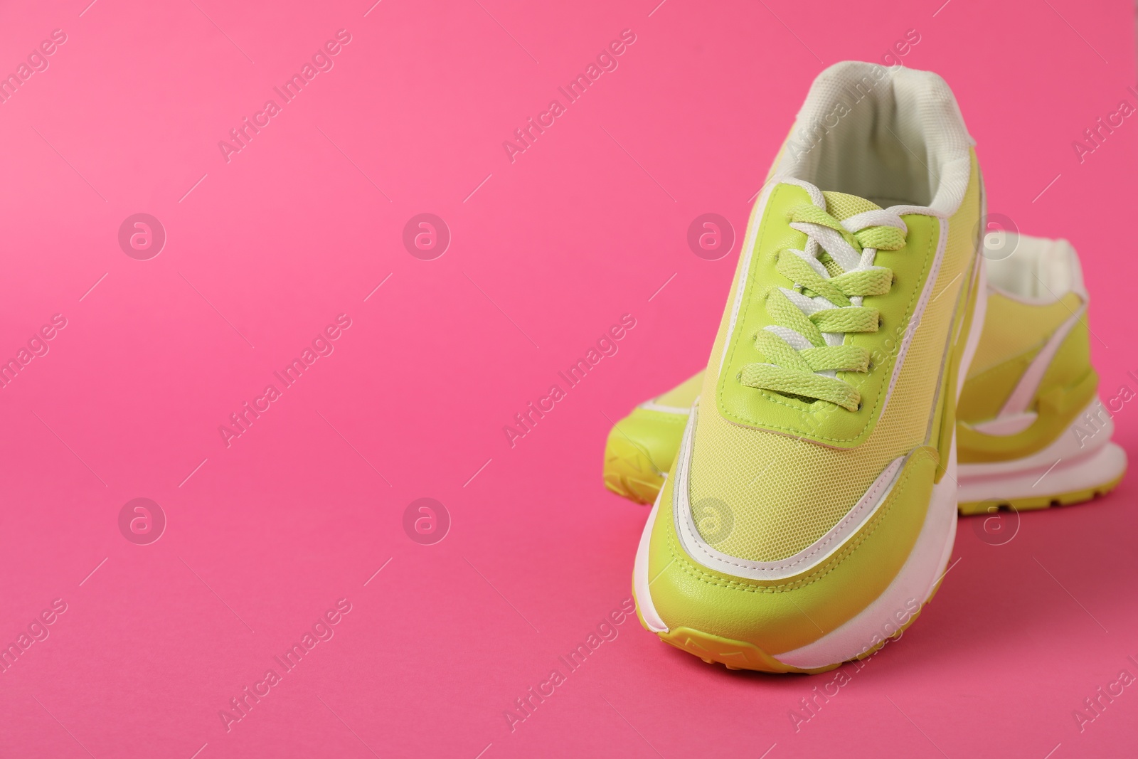 Photo of Sportive shoes. Green sneakers on pink background, space for text