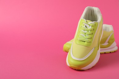 Photo of Sportive shoes. Green sneakers on pink background, space for text