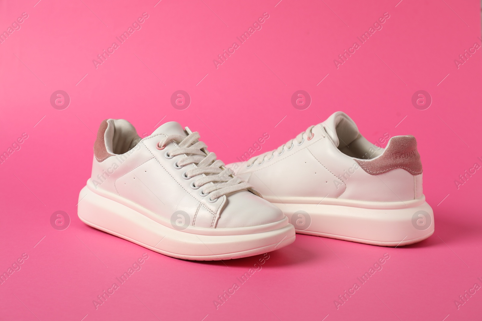 White sneakers on pink background. Sportive shoes Photo of White sneakers on pink background. Sportive shoes