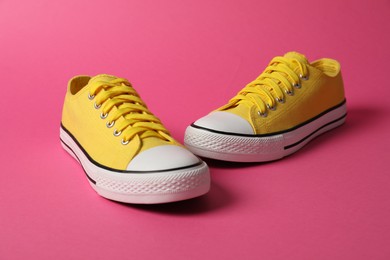 Photo of Yellow sneakers on pink background. Sportive shoes