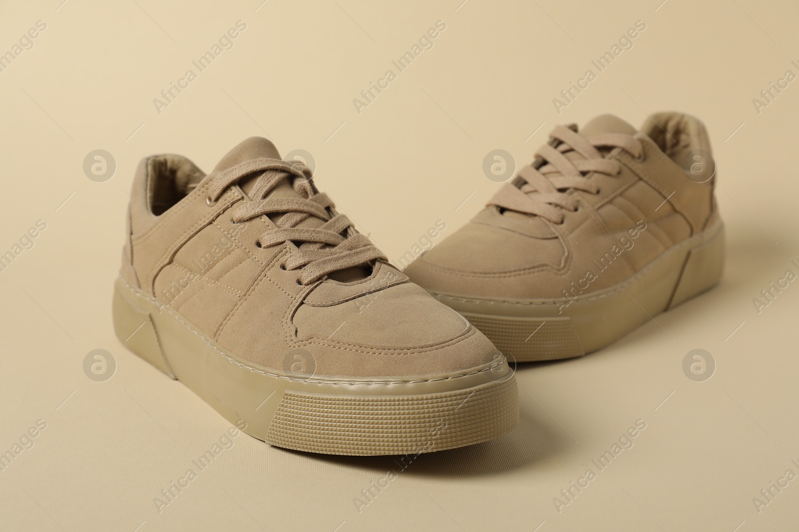 Photo of Stylish sneakers on beige background, closeup. Sportive shoes