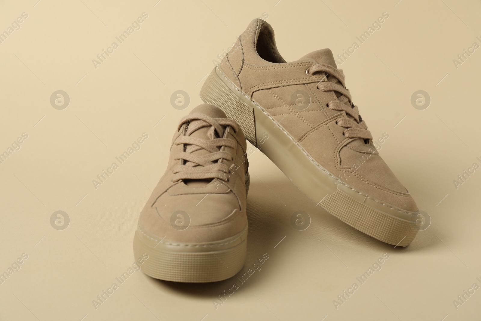 Photo of Stylish sneakers on beige background. Sportive shoes