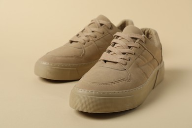 Photo of Stylish sneakers on beige background, closeup. Sportive shoes