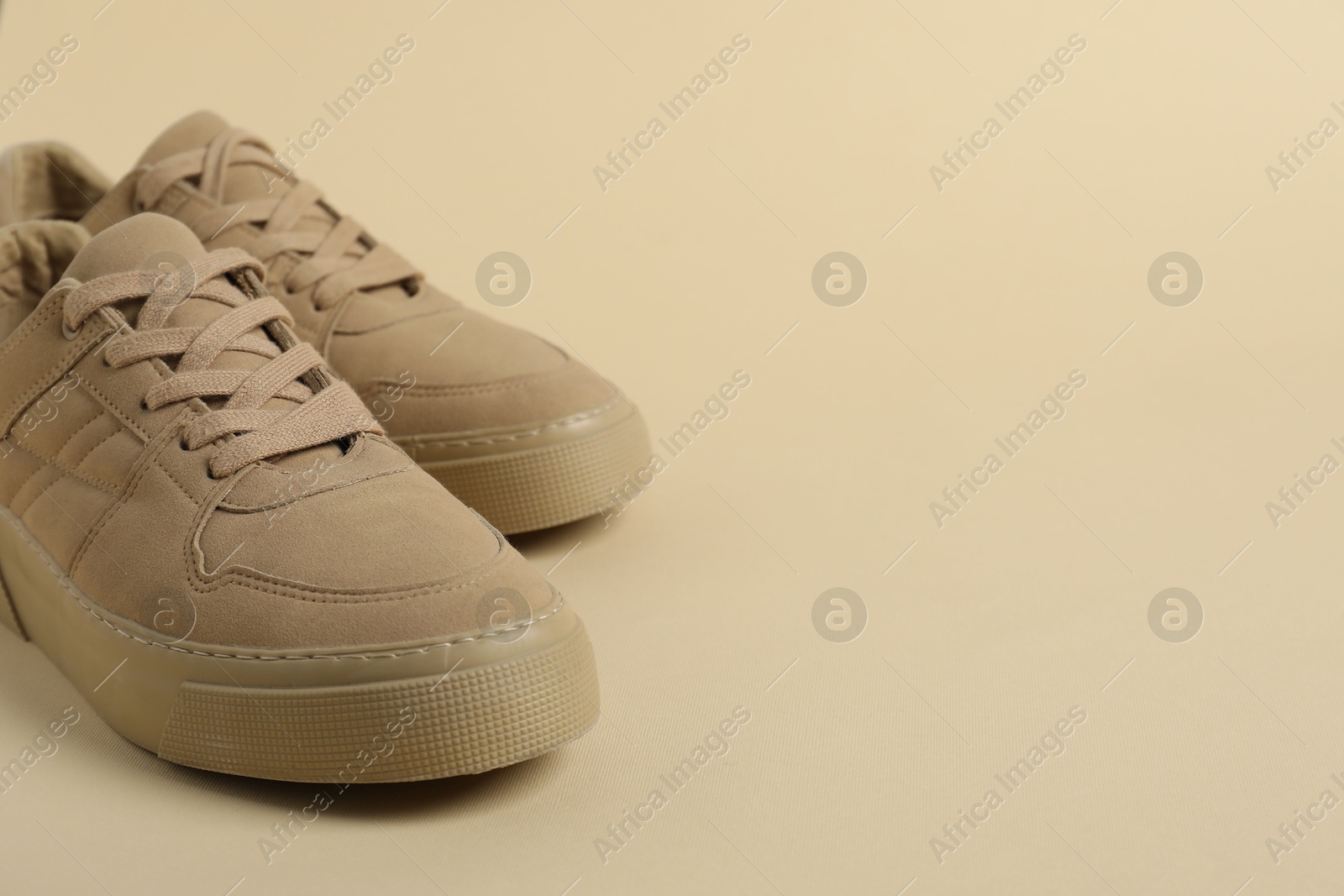 Photo of Sportive shoes. Stylish sneakers on beige background, closeup. Space for text