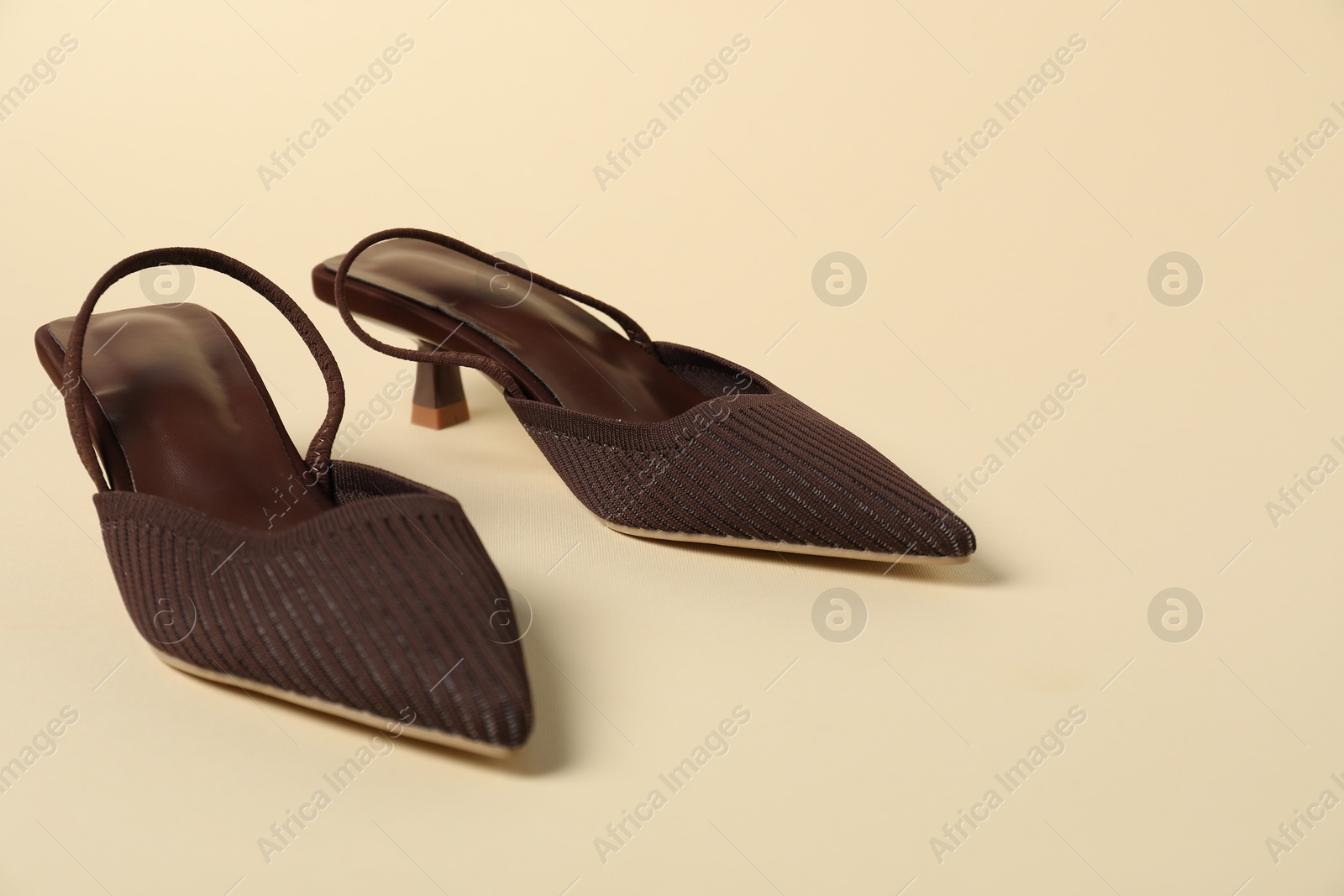 Photo of Pair of brown high heeled shoes on beige background