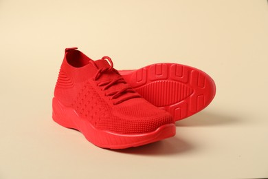 Photo of Red sneakers on beige background. Sportive shoes