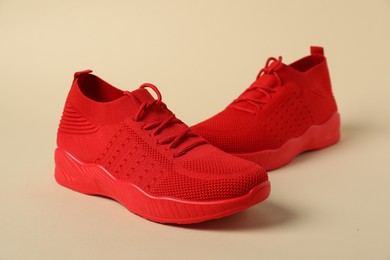 Photo of Red sneakers on beige background. Sportive shoes