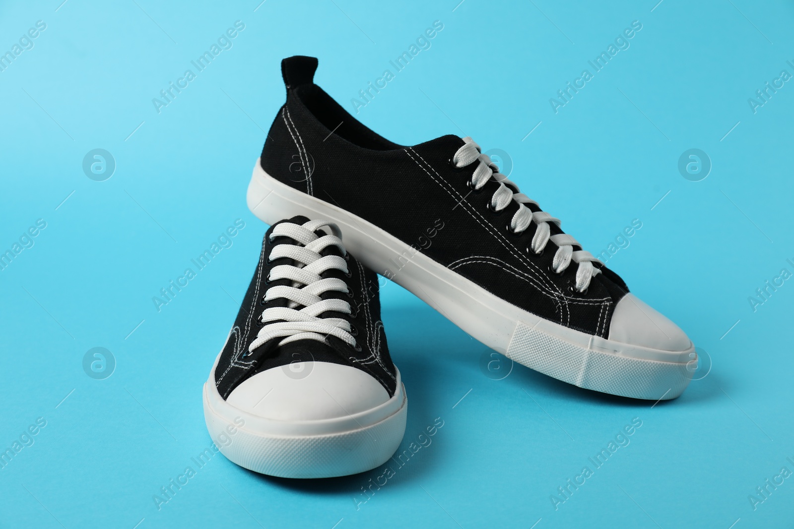 Photo of Black sneakers on light blue background. Sportive shoes