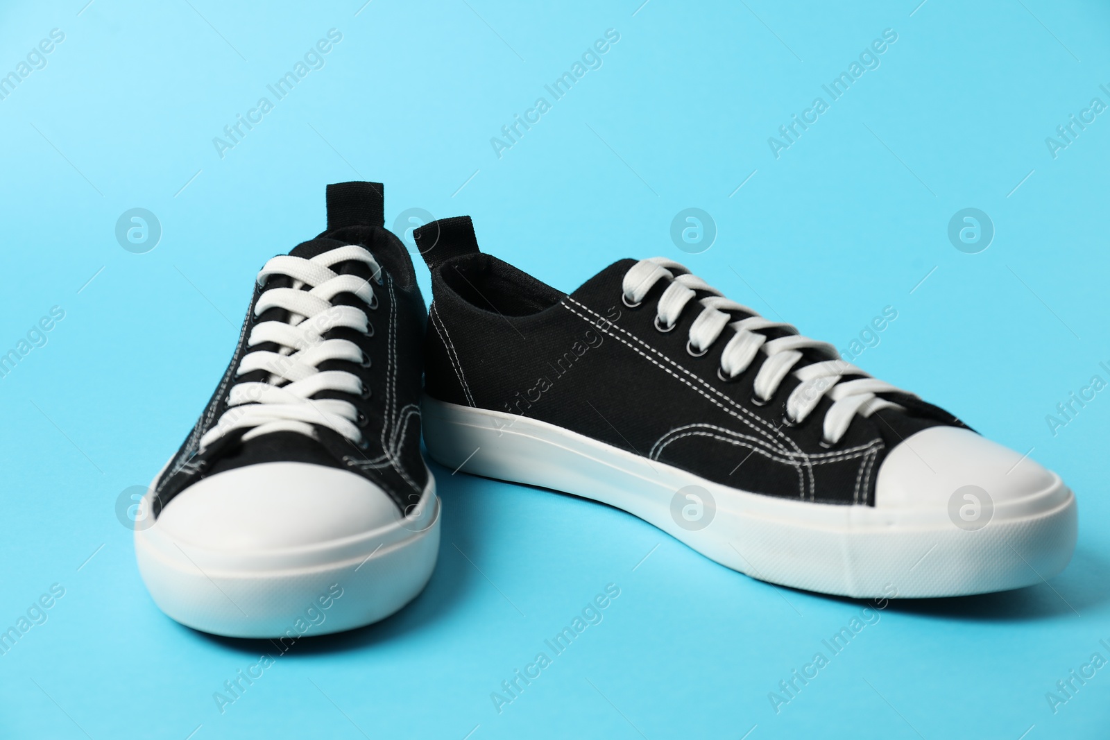 Photo of Black sneakers on light blue background. Sportive shoes