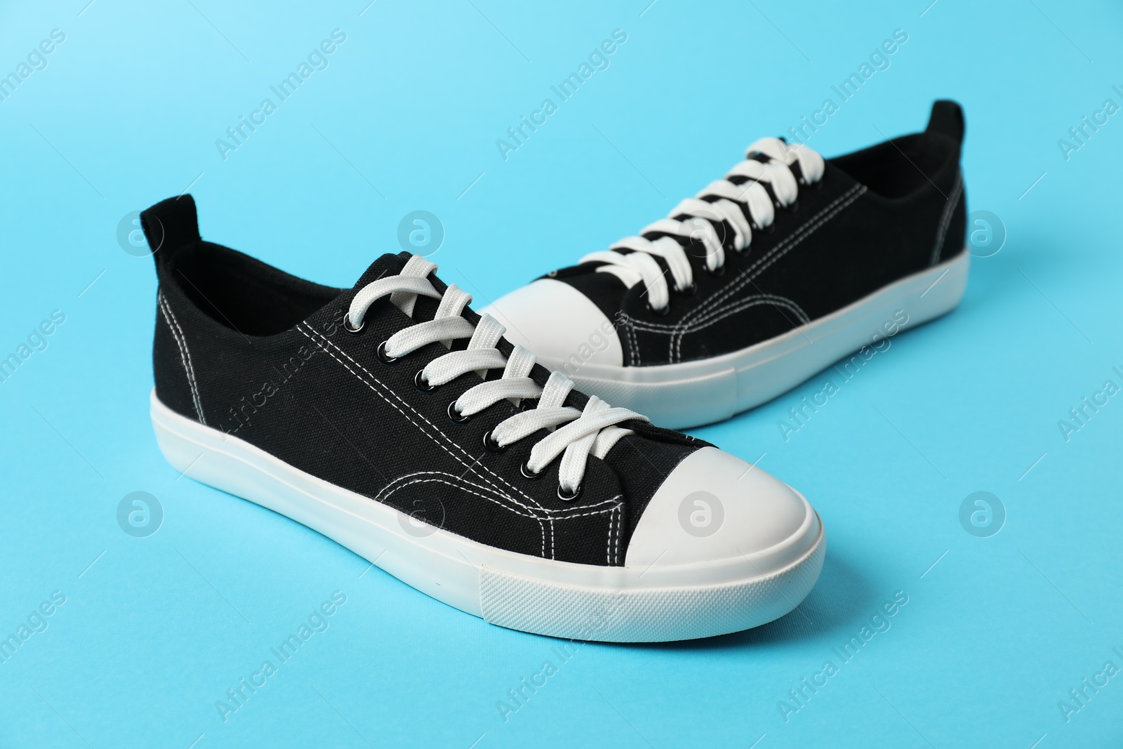 Photo of Black sneakers on light blue background. Sportive shoes