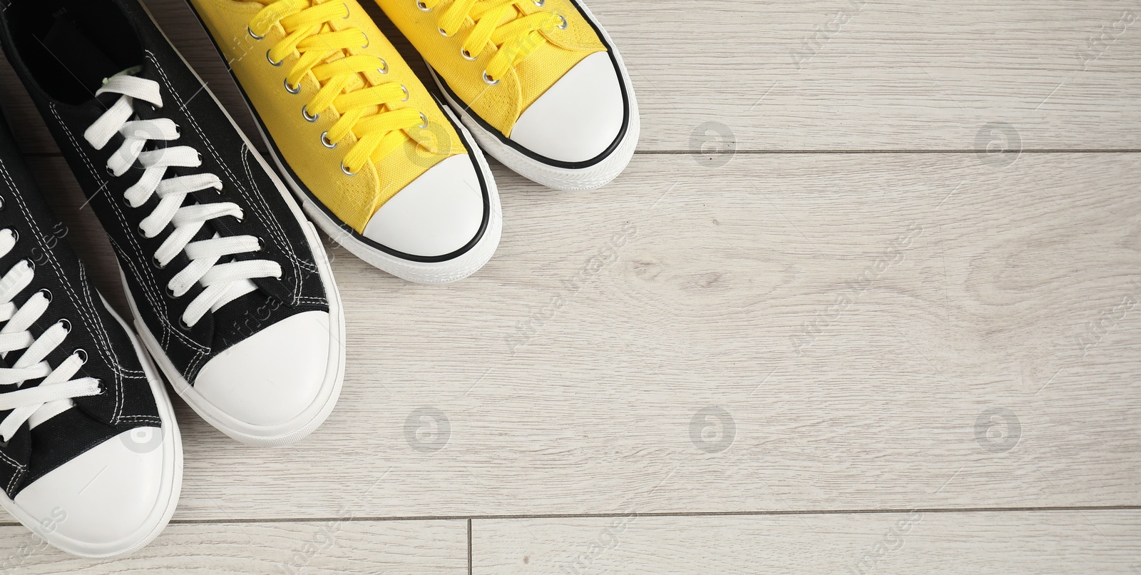 Photo of Sportive shoes. Different sneakers on wooden background, flat lay. Space for text