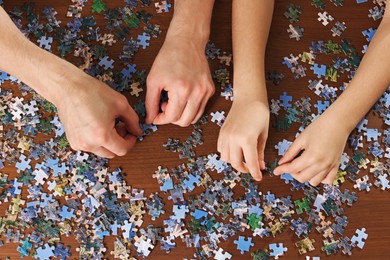 Photo of Father and his daughter solving puzzle together at wooden table, top view