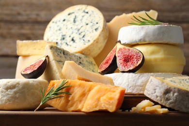 Photo of Different types of cheese, figs and rosemary on table, closeup