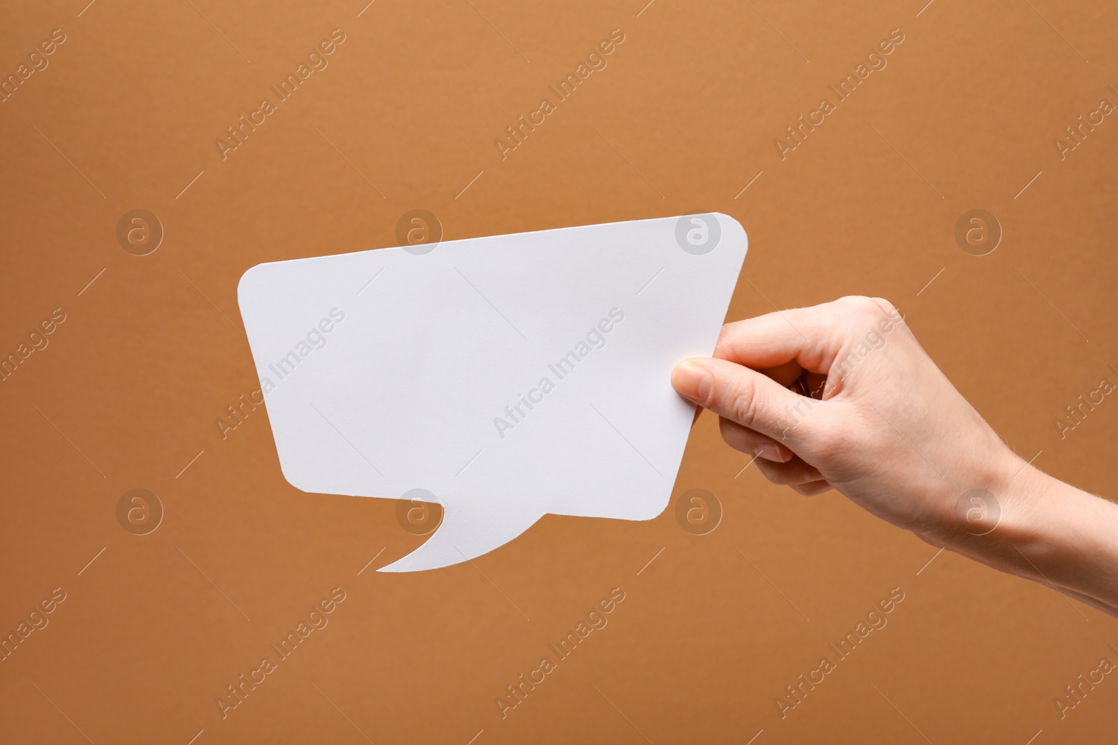 Photo of Woman holding blank speech bubble on brown background, closeup. Space for text