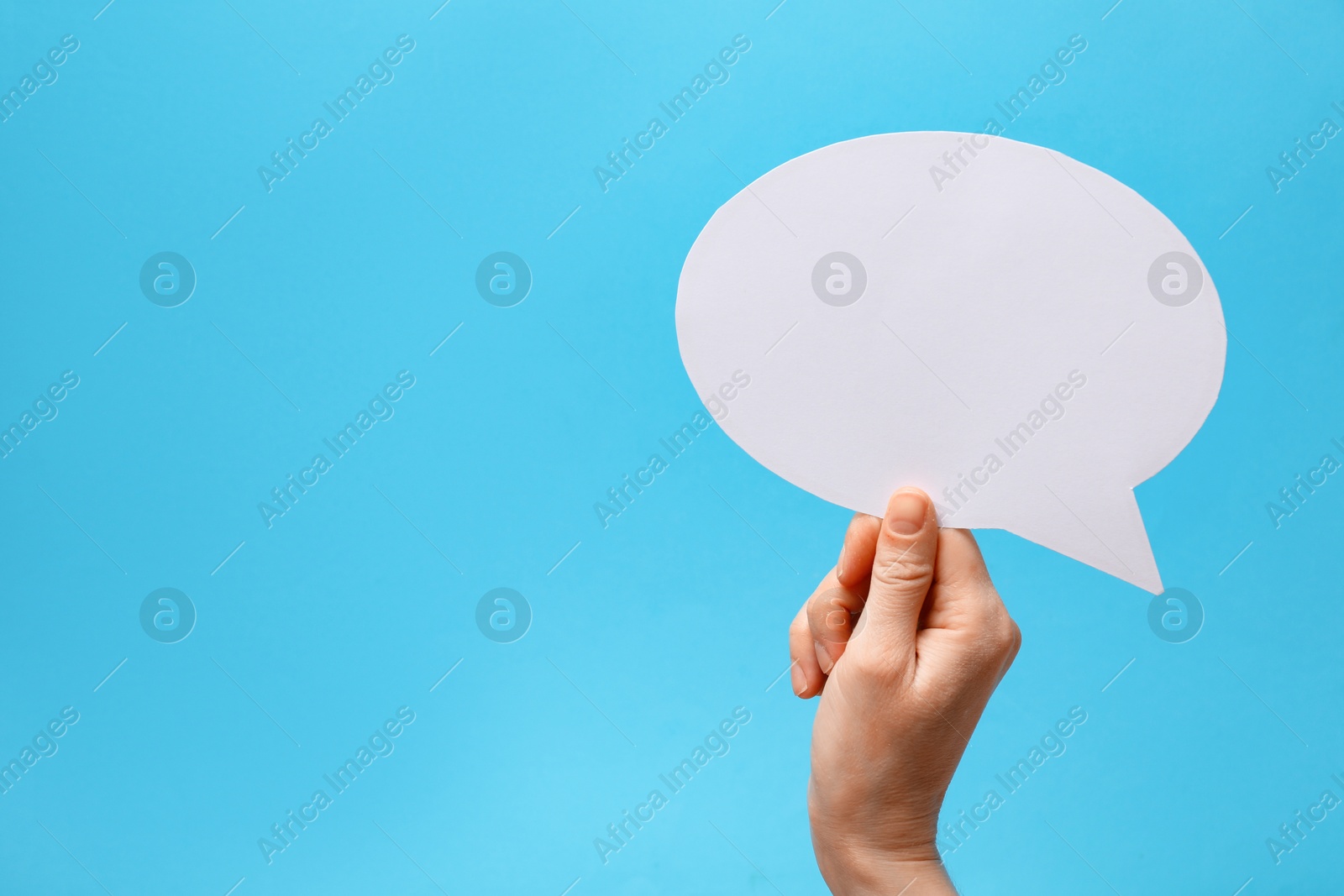 Photo of Woman holding blank speech bubble on light blue background, closeup. Space for text