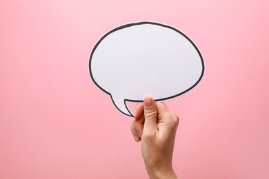 Photo of Woman holding blank speech bubble on light pink background, closeup. Space for text