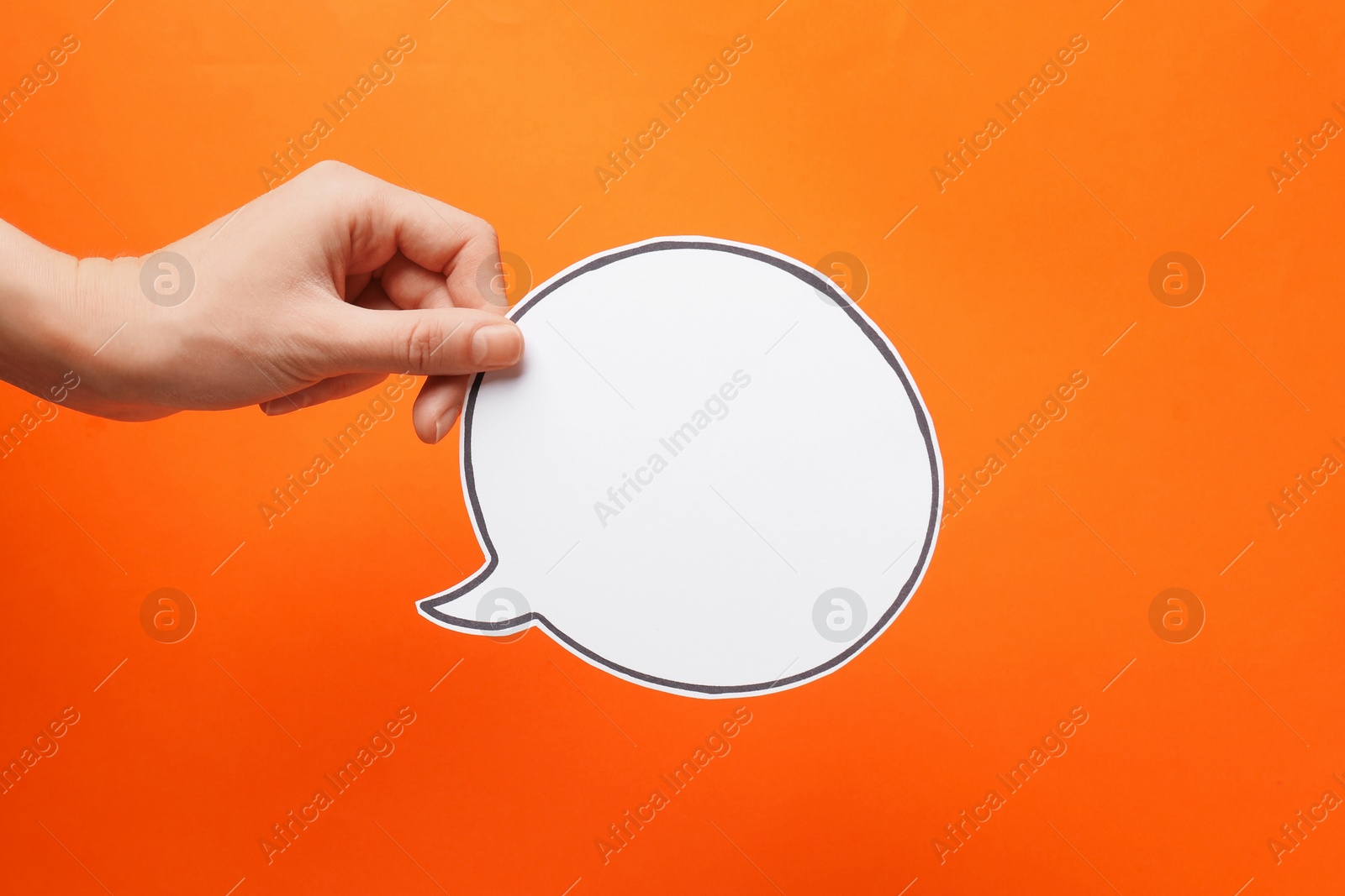 Photo of Woman holding blank speech bubble on orange background, closeup. Space for text