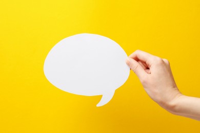 Photo of Woman holding blank speech bubble on yellow background, closeup. Space for text