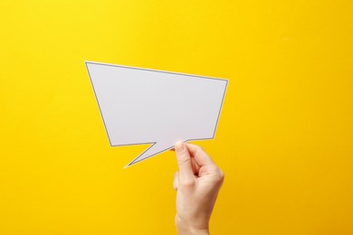 Photo of Woman holding blank speech bubble on yellow background, closeup. Space for text