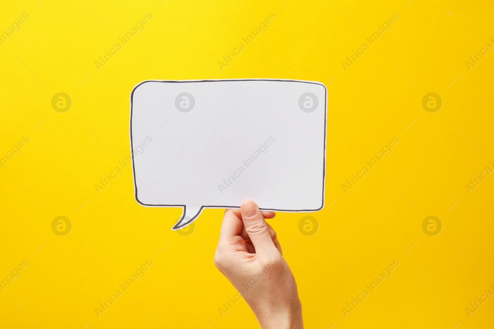 Photo of Woman holding blank speech bubble on yellow background, closeup. Space for text