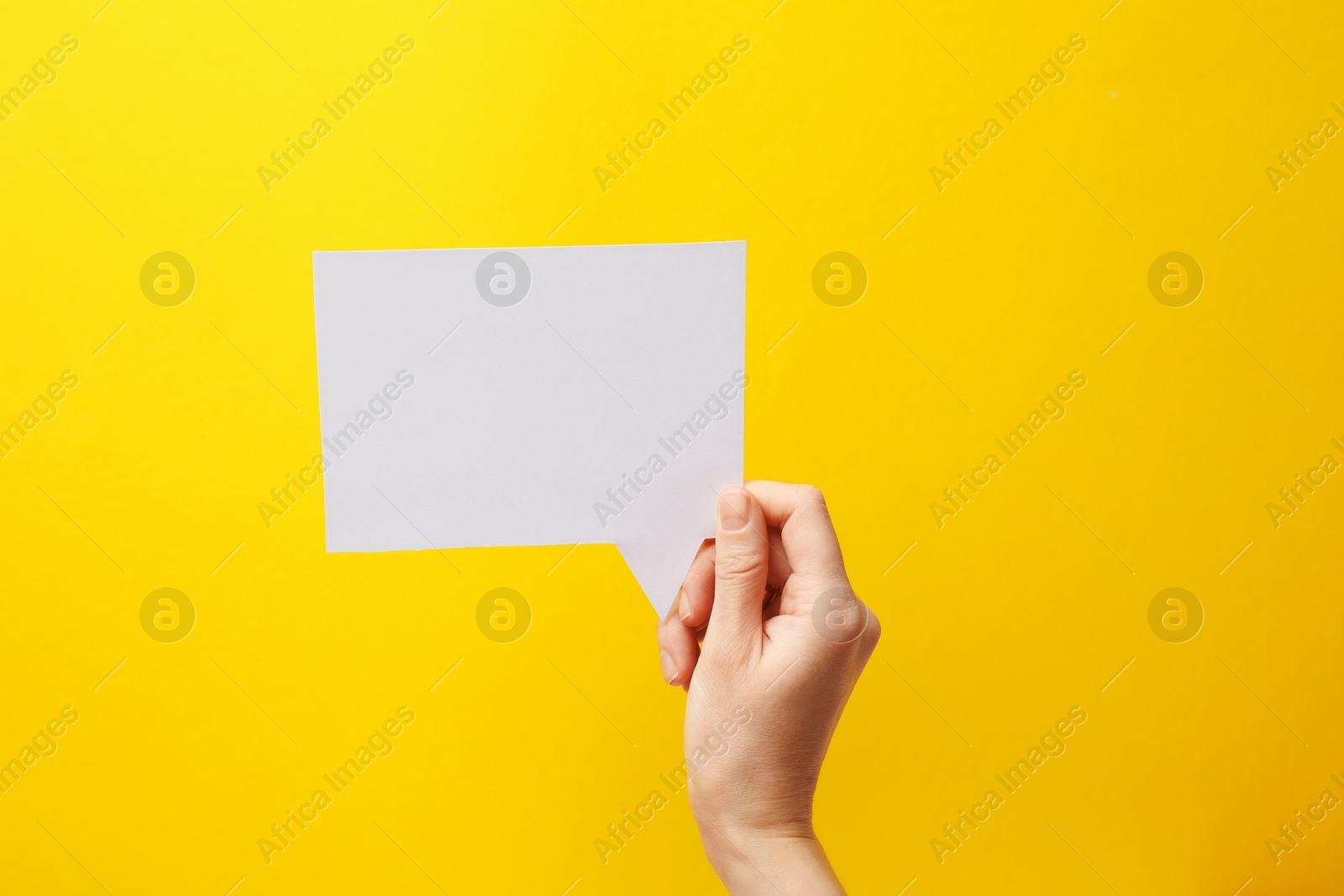 Photo of Woman holding blank speech bubble on yellow background, closeup. Space for text